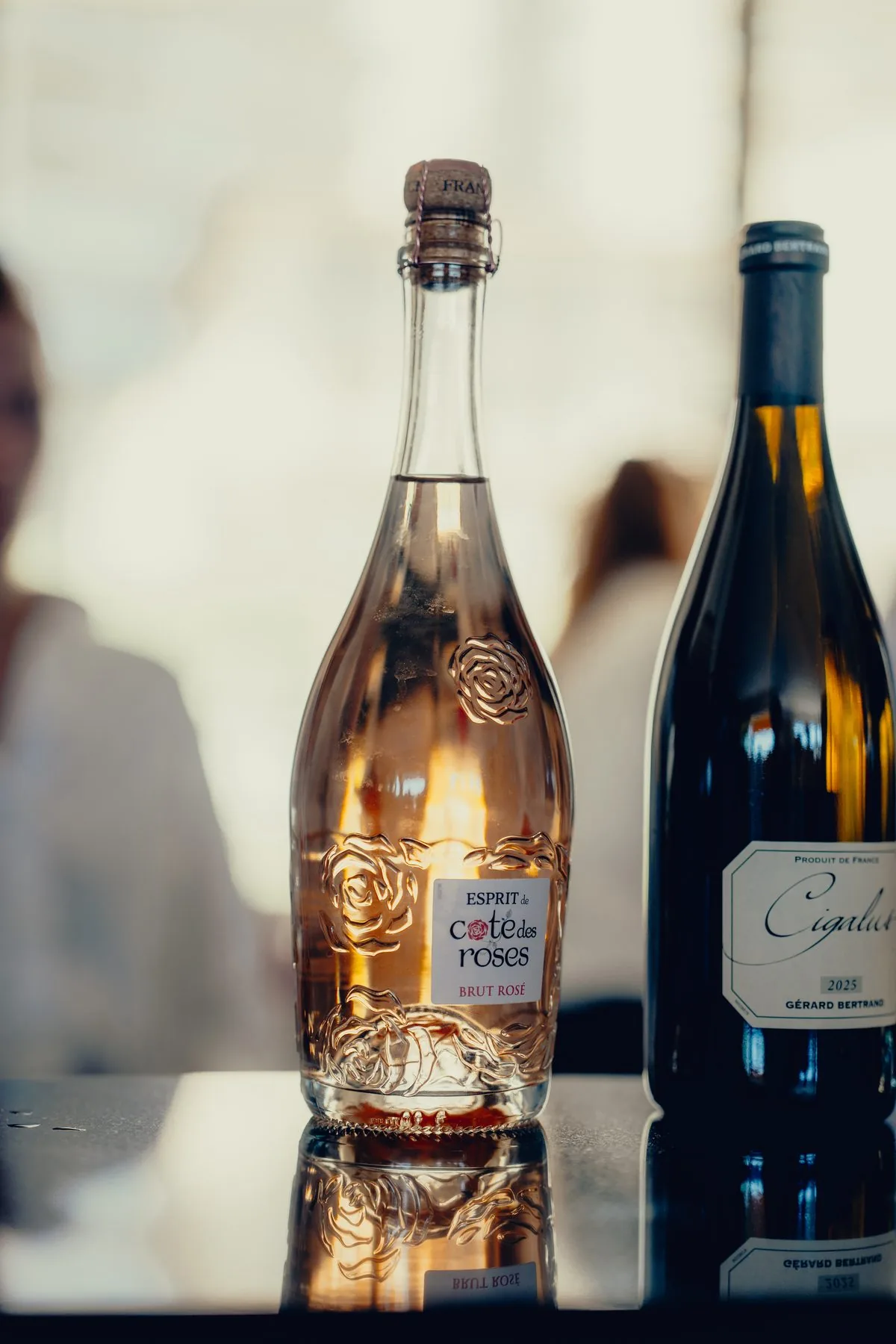 A bottle of sparkling rosé and a bottle of red wine on a hospitality table